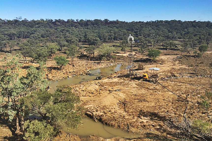 An aerial photo of a damaged dam and windmill on a grazing property