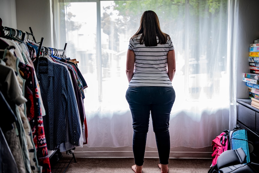 Jen stands at a window, with her silhouette clearly visible. 