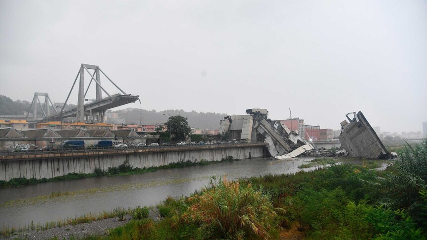 The rubble of the collapsed bridge sits in a river