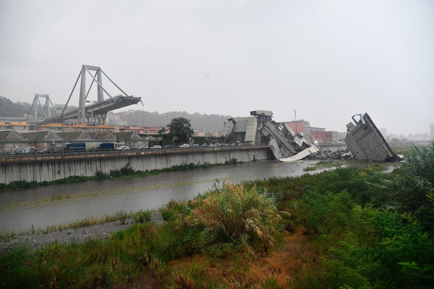 The rubble of the collapsed bridge sits in a river