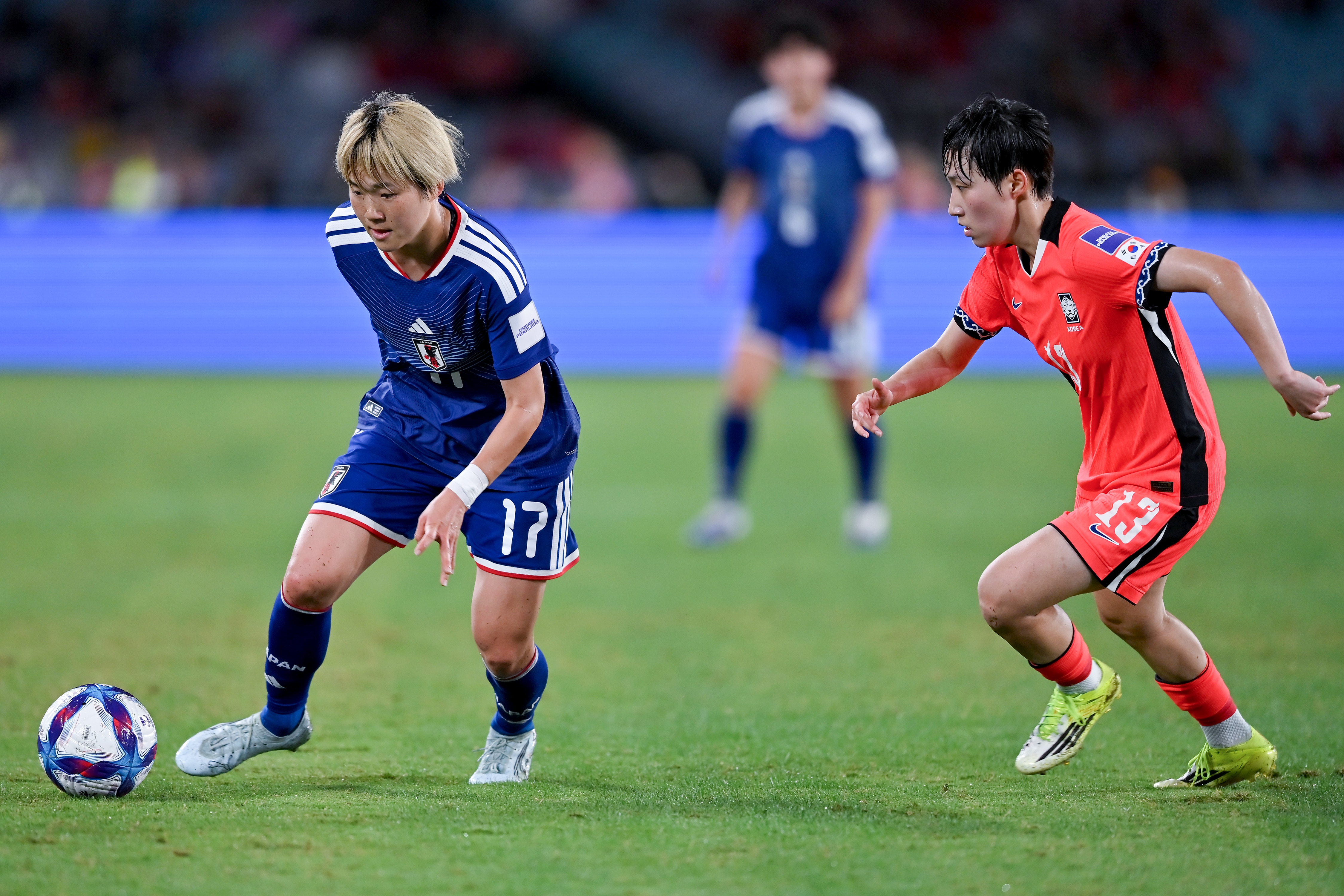 Um jogador de futebol de azul controla a bola
