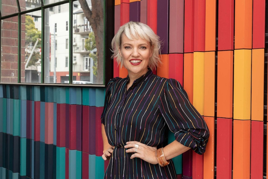 Jacinta Parsons smiles while standing in front of a colourful wall