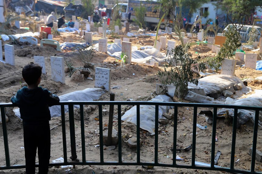 picture of a child standing in front of graves in Gaza