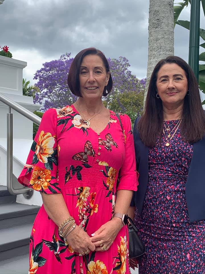 Two women standing together in bright coloured dresses
