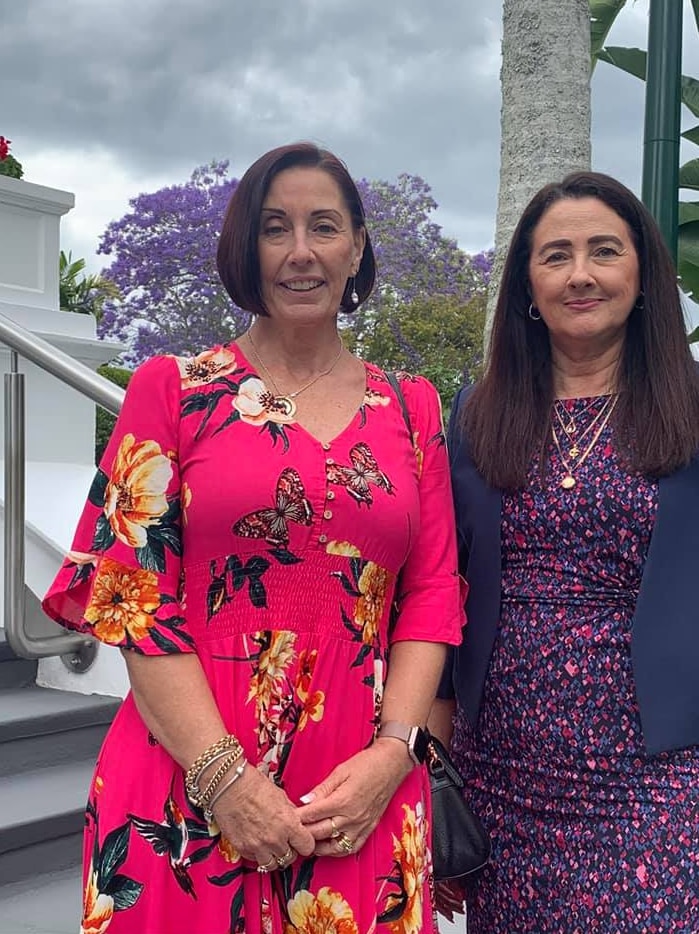 Two women standing together in bright coloured dresses