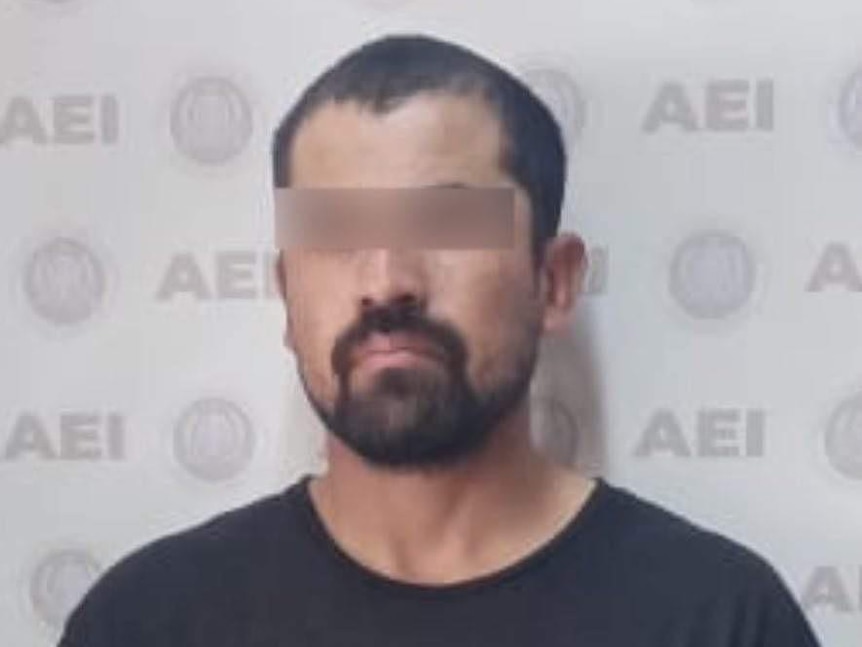 A mugshot of a bearded man wearing a black t-shirt, with a blurred bar over his eyes.
