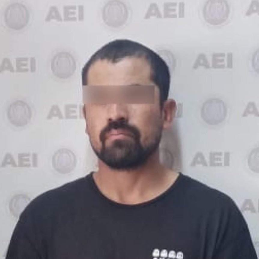 A mugshot of a bearded man wearing a black t-shirt, with a blurred bar over his eyes.
