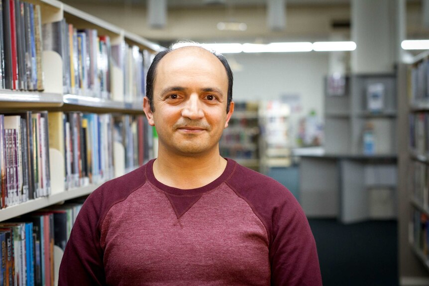 A man stands in the aisle of a Library.