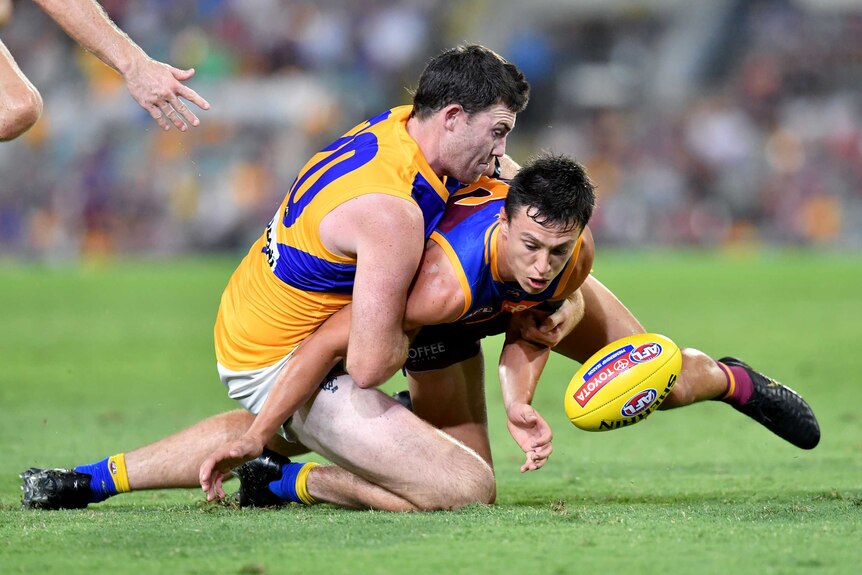 Jeremy McGovern of the Eagles tackles Brisbane's Hugh McCluggage.