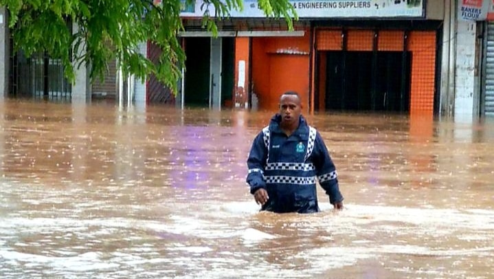 Police officer walking in flood water.