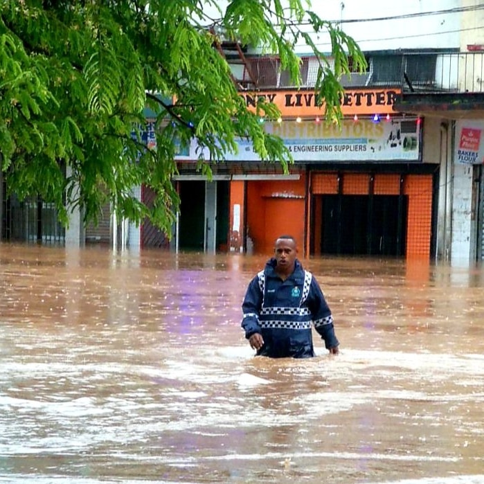 Police officer walking in flood water.