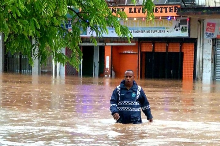 A rescue police officer waste deep in flood water in Fiji.