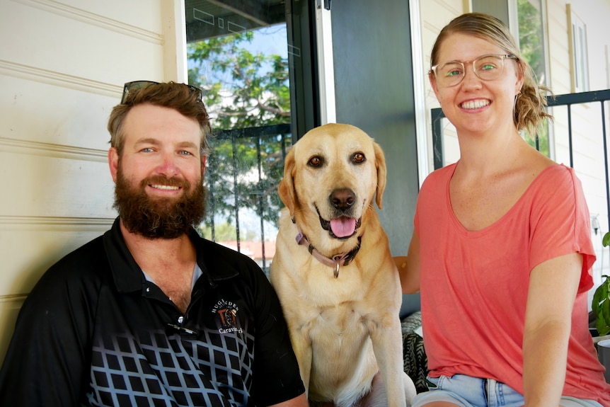 A man, woman and dog sit on the steps of a house