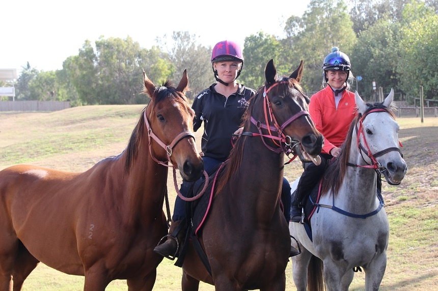 Two women sit on horses with one other horse next to them