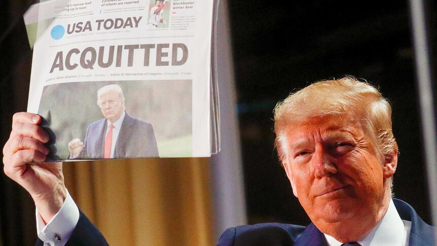 Donald Trump holding a newspaper up with the headline "Acquitted"