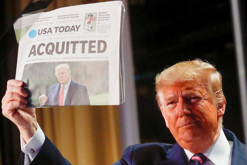 Donald Trump holding a newspaper up with the headline "Acquitted"