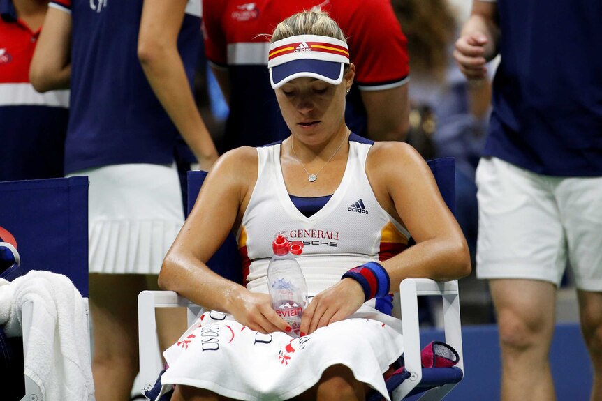 Angelique Kerber sitting down and staring at a water bottle in her hands at the change of ends.