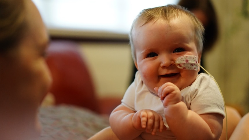 Baby with nasogastric tube sits on mother's lap