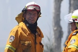 Tony Abbott, wearing protective fire gear, stands with another firefighter. There is ash all over his uniform.