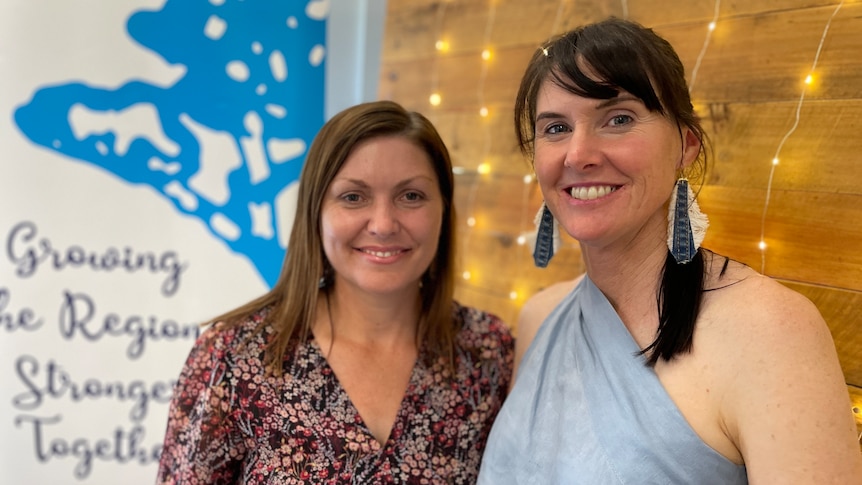 A mid shot of two women standing next to each other with a blurred background 