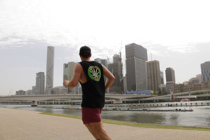 A man jogging by Brisbane River in South Bank