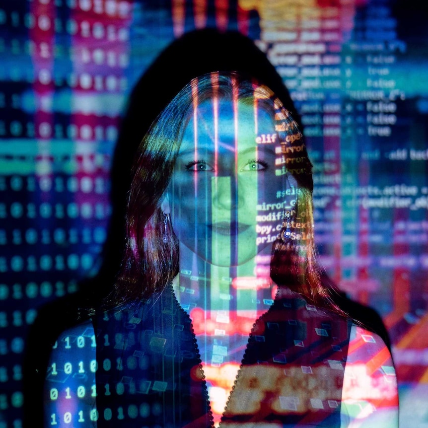 Woman staring into camera with a slide of coloured coding projected on her.
