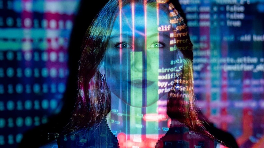 Woman staring into camera with a slide of coloured coding projected on her.