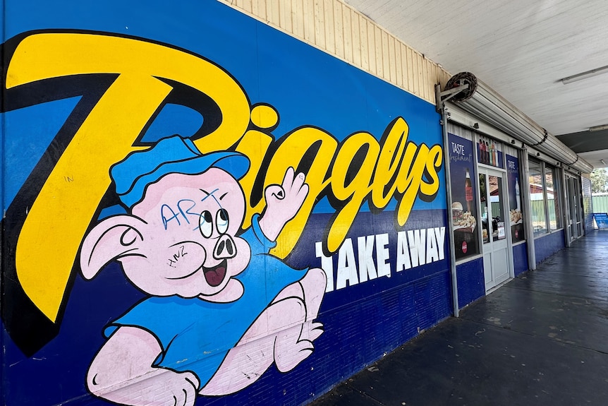 Вывеска на фасаде магазина бутылок с надписью Piggly's и изображением свиньи.