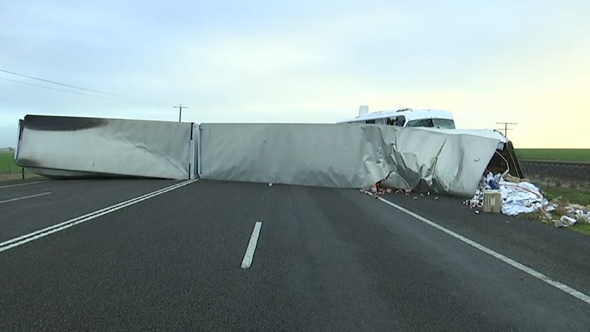 White truck trailers lie across both lanes of the Western Highway, entirely blocking the road.