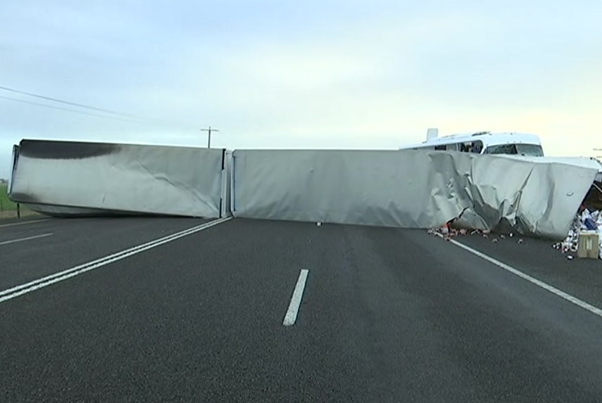 White truck trailers lie across both lanes of the Western Highway, entirely blocking the road.