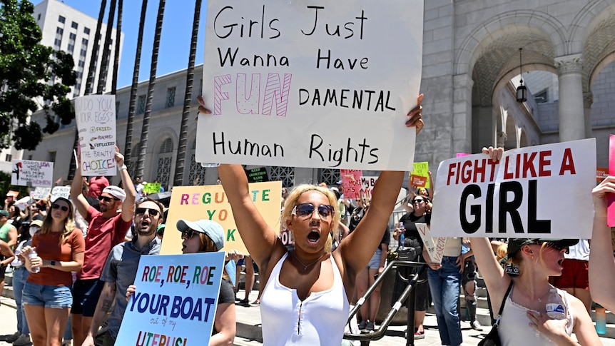 An activist holds up a sign which reads Girls Just Wanna Have FUNDamental Human Rights