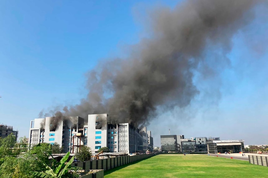 Smoke billows out of building in distance.