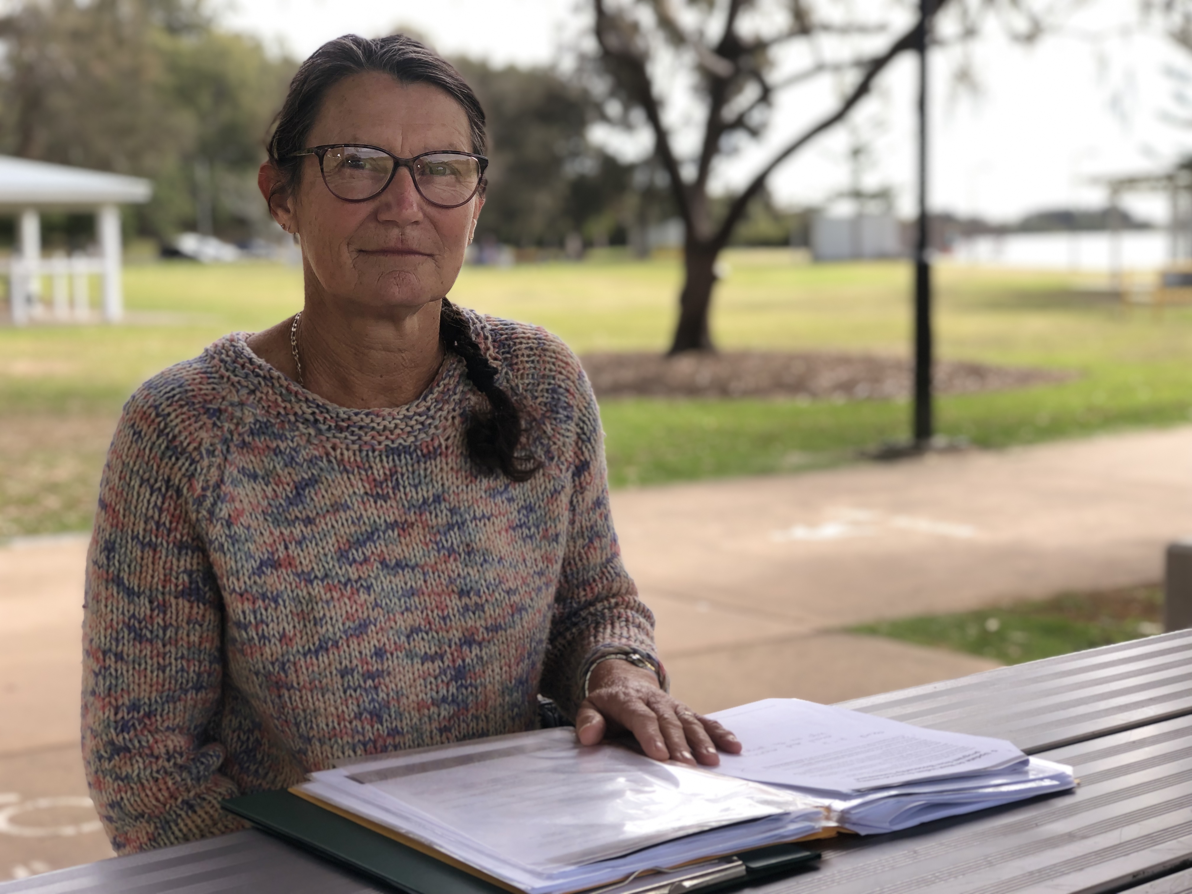 A worried looking lady is sitting at a picnic table with all of the paperwork she'd collected at the end of the program.