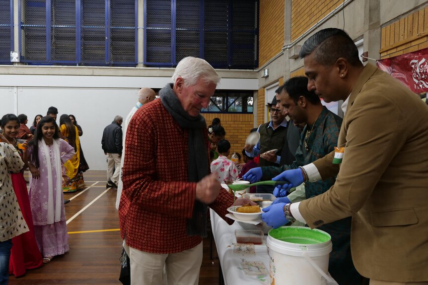 Older western man being served food by an Indian man