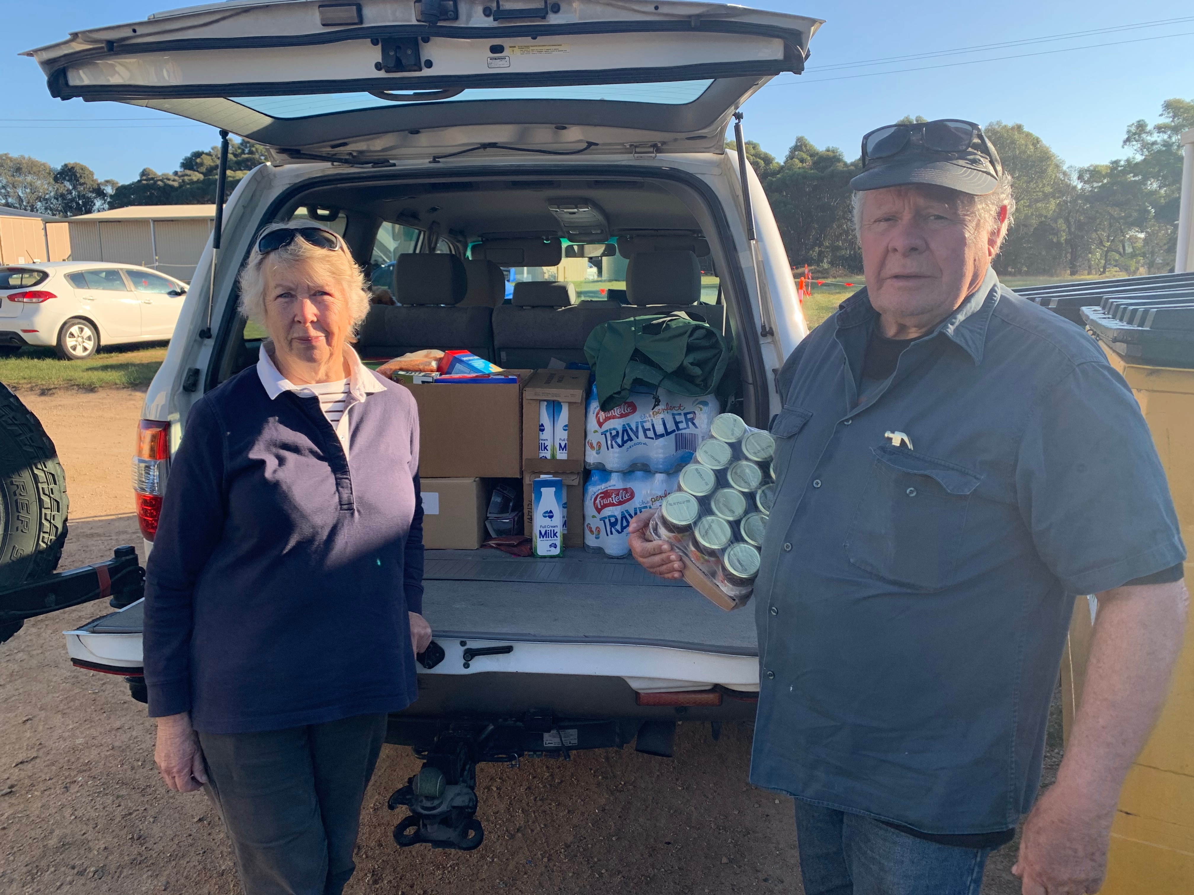 man and woman stand at the boot of their truck