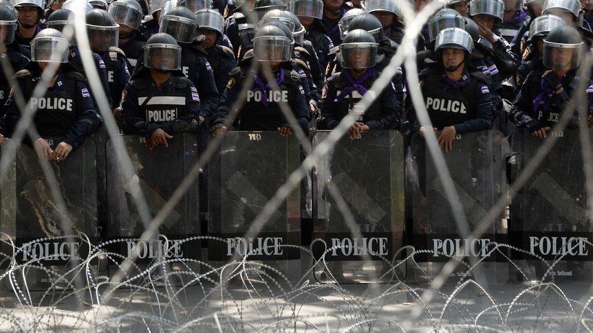 Policemen form a line behind barbed wires inside police headquarters during an anti-government protest in Bangkok