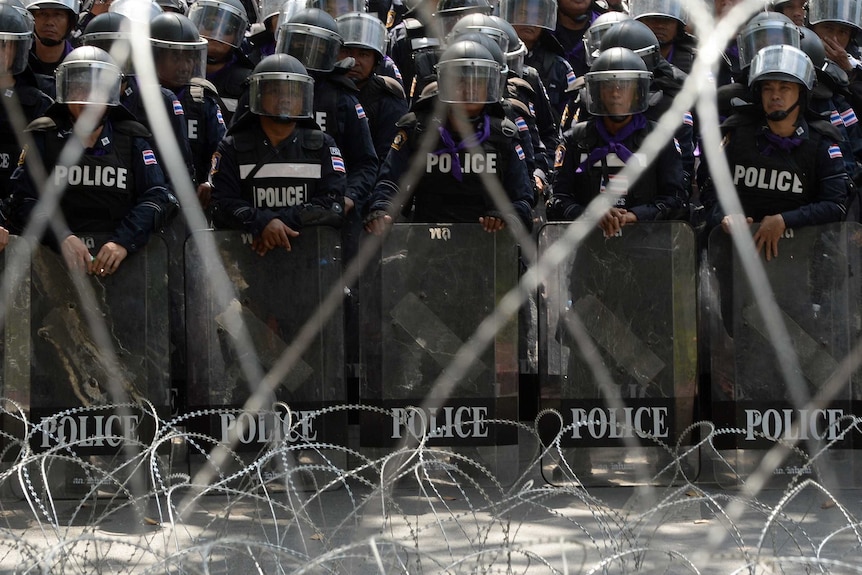 Policemen form a line behind barbed wires inside police headquarters during an anti-government protest in Bangkok