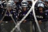 Policemen form a line behind barbed wires inside police headquarters during an anti-government protest in Bangkok