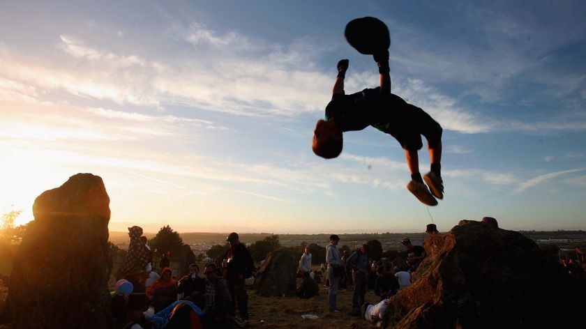 A festival goer jumps off a stone at the Glastonbury Festival