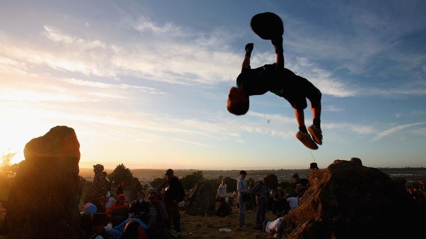 A festivalgoer jumps off a stone at the Glastonbury festival