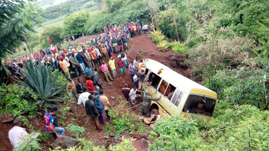 Local residents stand around the damaged bus.