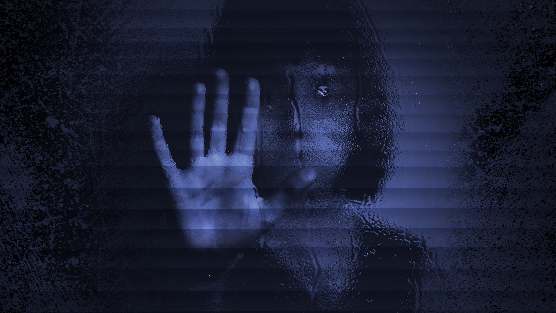 A blurred, dark photo of a child holding her hand up behind a glass screen.