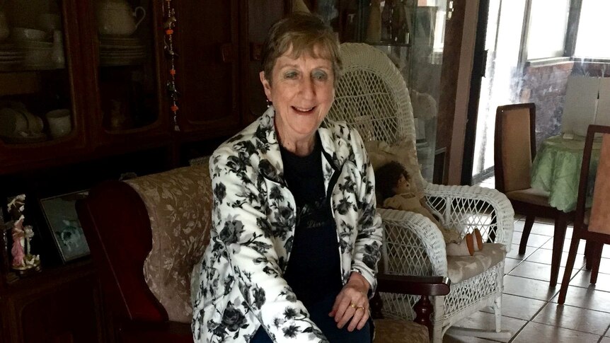 Toni Donnelly sits in a chair with two greyhounds at her feet.