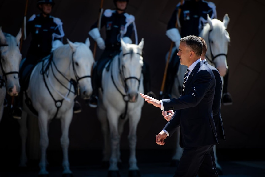 The premier walking with police horses in the background