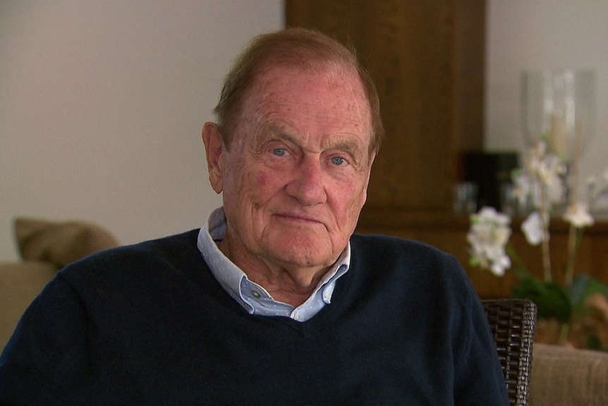 A man in a blue jumper sitting in a living room