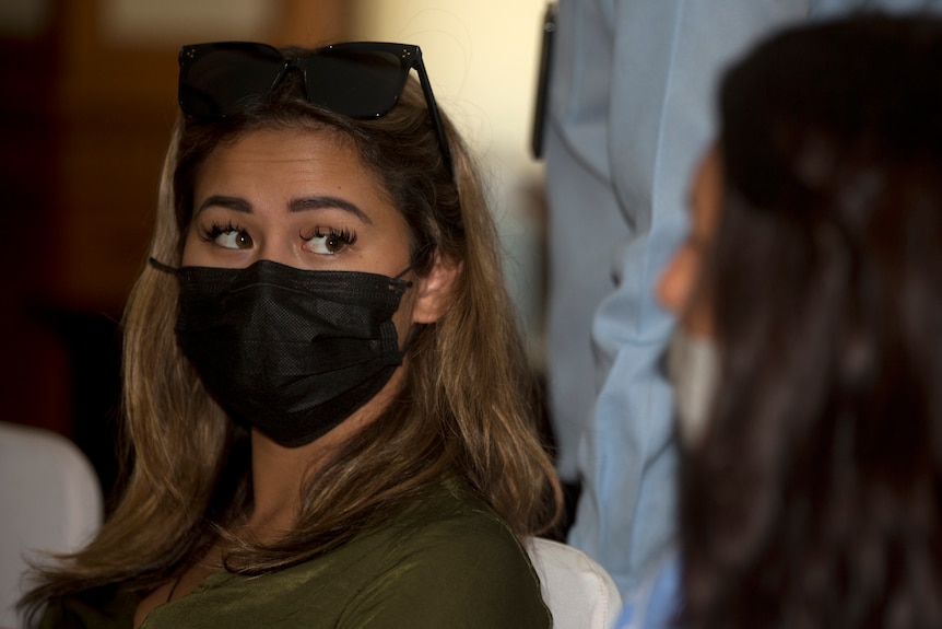A woman in a face mask looks at her lawyer 