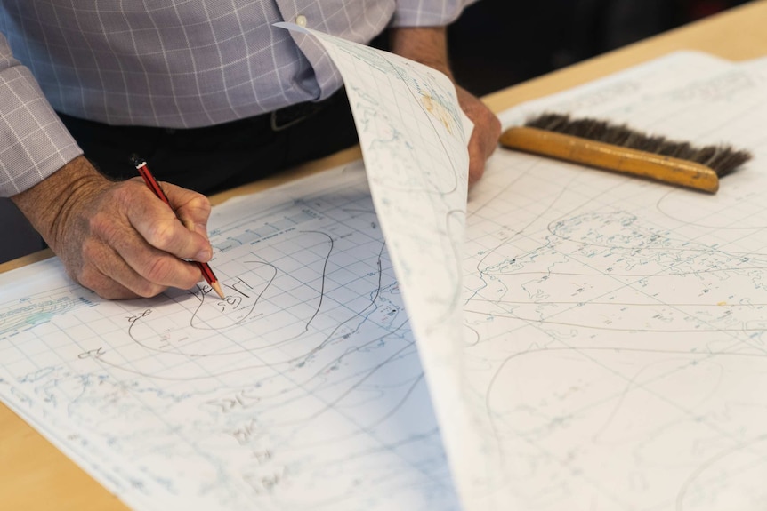 Mike Bergin draws markings on a large weather map.