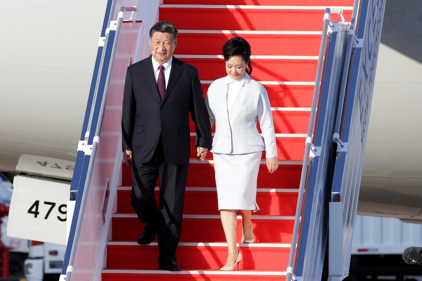 Xi Jinping and Peng Liyuan hold hands. 