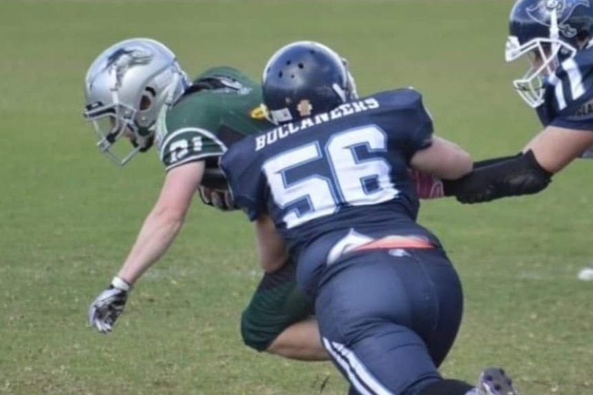 A female gridiron player makes a rush with the ball during a game.