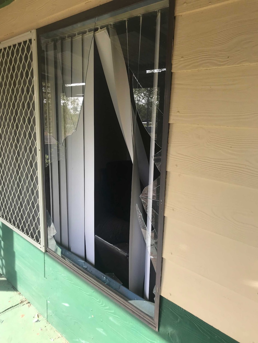 A broken glass window on a weatherboard house.